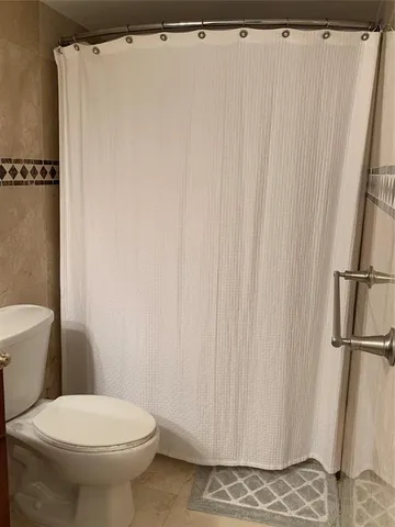 a white toilet sitting next to a shower