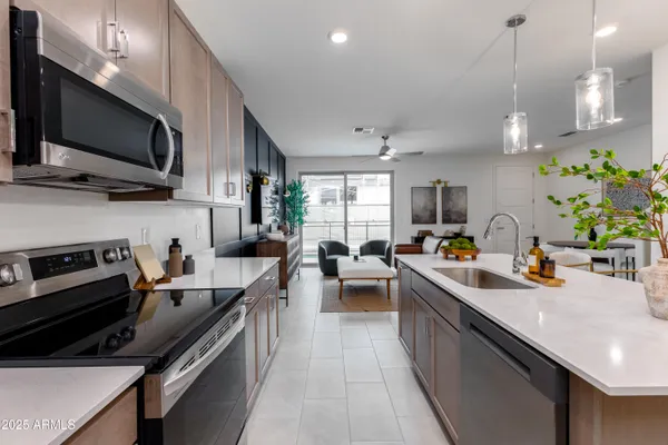 a kitchen with stainless steel appliances a sink dishwasher a stove top oven a refrigerator with wooden floor and cabinets