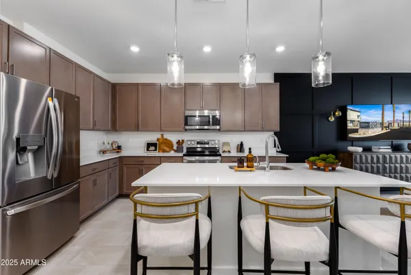 a kitchen with refrigerator a stove a sink and chairs