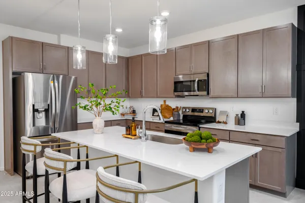 a kitchen with a sink a refrigerator and chairs