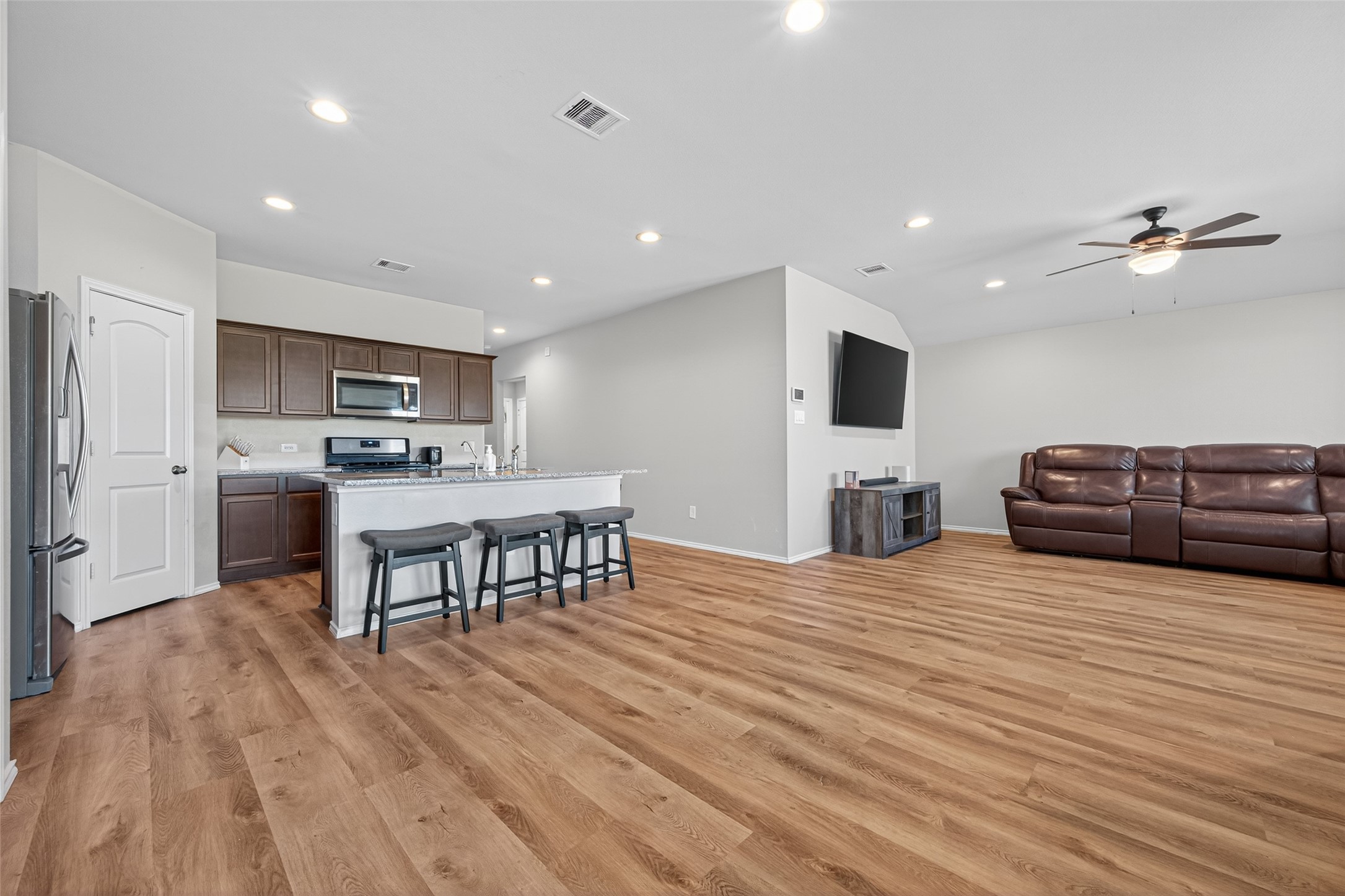 23706 Blodgett Peak Trail Spring, TX 77373 - Photo 8 of 31 An open-concept living area with wood flooring, a modern kitchen featuring stainless steel appliances and a large island with bar seating. The space is well-lit with recessed lighting.