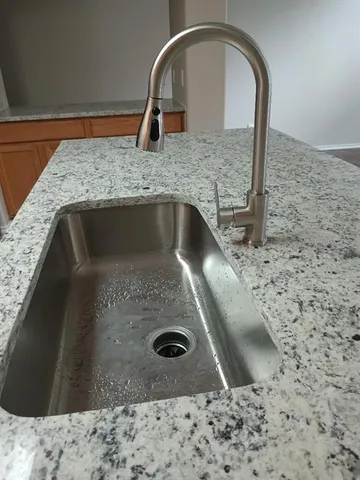 a kitchen with a sink a stove top oven and wooden cabinets