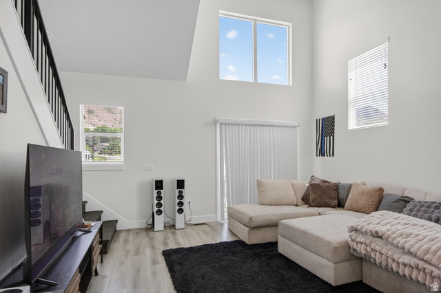 2811 South Orch Hl Lane Perry, UT 84302 - Photo 4 of 18 Spacious living area featuring high ceilings, white walls, wood-finish flooring, and a sliding glass door with vertical blinds
