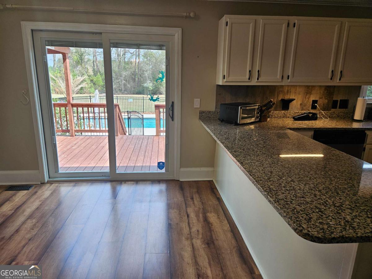 2001 Rutland Road, Unit 1 Tifton, GA 31793 - Photo 33 of 51 a kitchen with granite countertop a stove a sink and a microwave