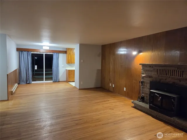 an empty room with wooden floor fireplace and windows