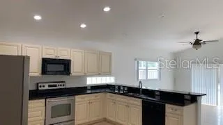 a kitchen with granite countertop a sink stainless steel appliances and white cabinets