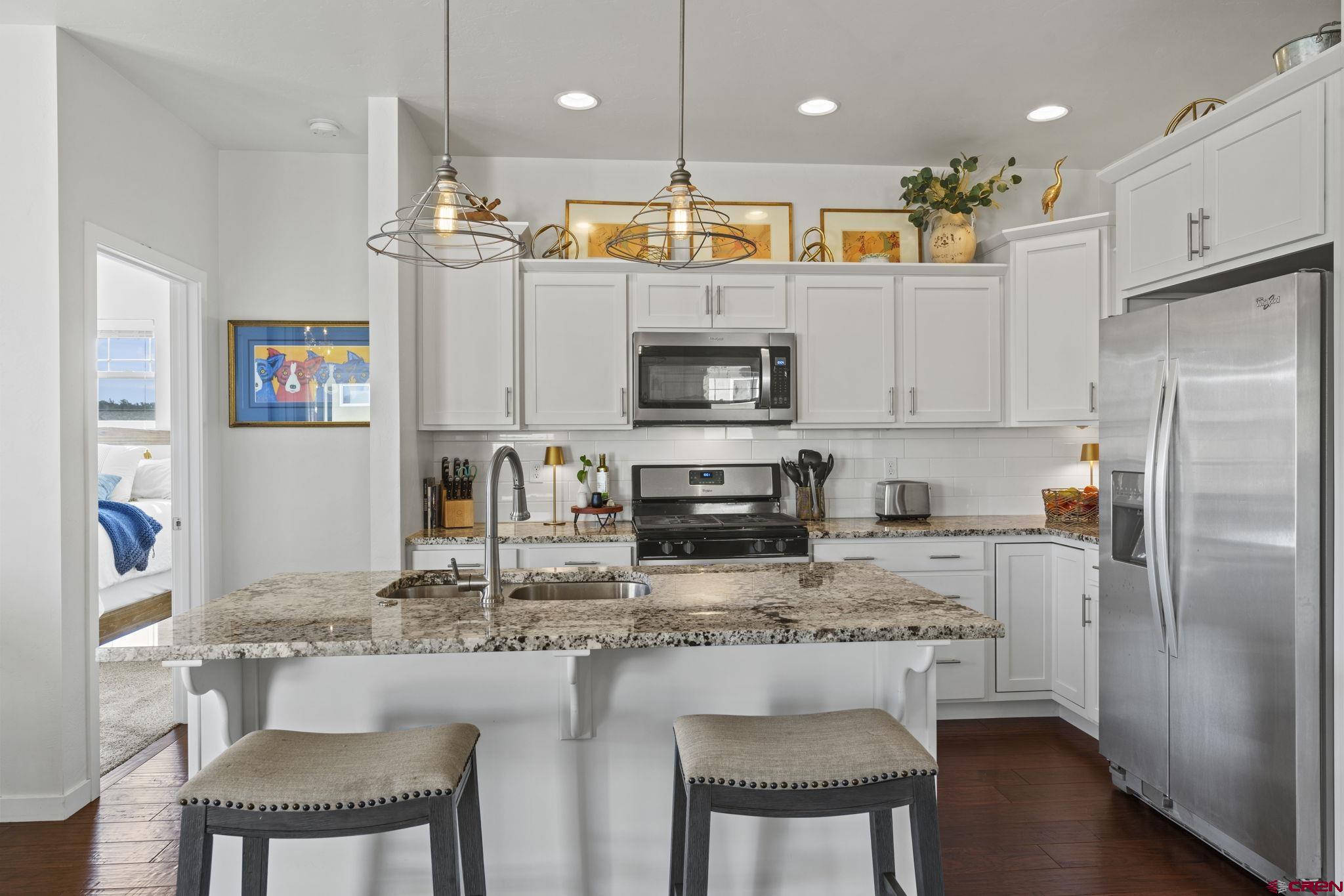 155 Prospector Avenue Durango, CO 81301 - Photo 5 of 35 a kitchen with stainless steel appliances granite countertop a stove top oven a refrigerator a sink and a dining table with wooden floor