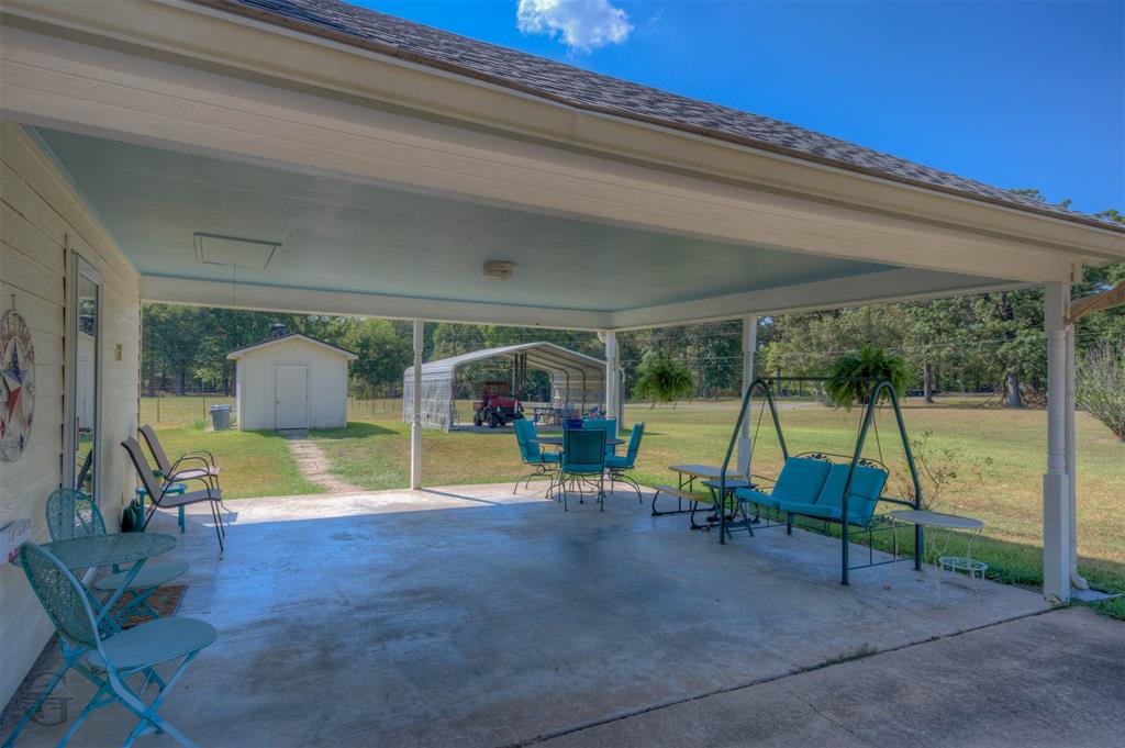 8835 Sebastian Road Keithville, LA 71047 - Photo 4 of 21 Expansive covered concrete patio with an adjacent storage shed and a separate open-sided structure