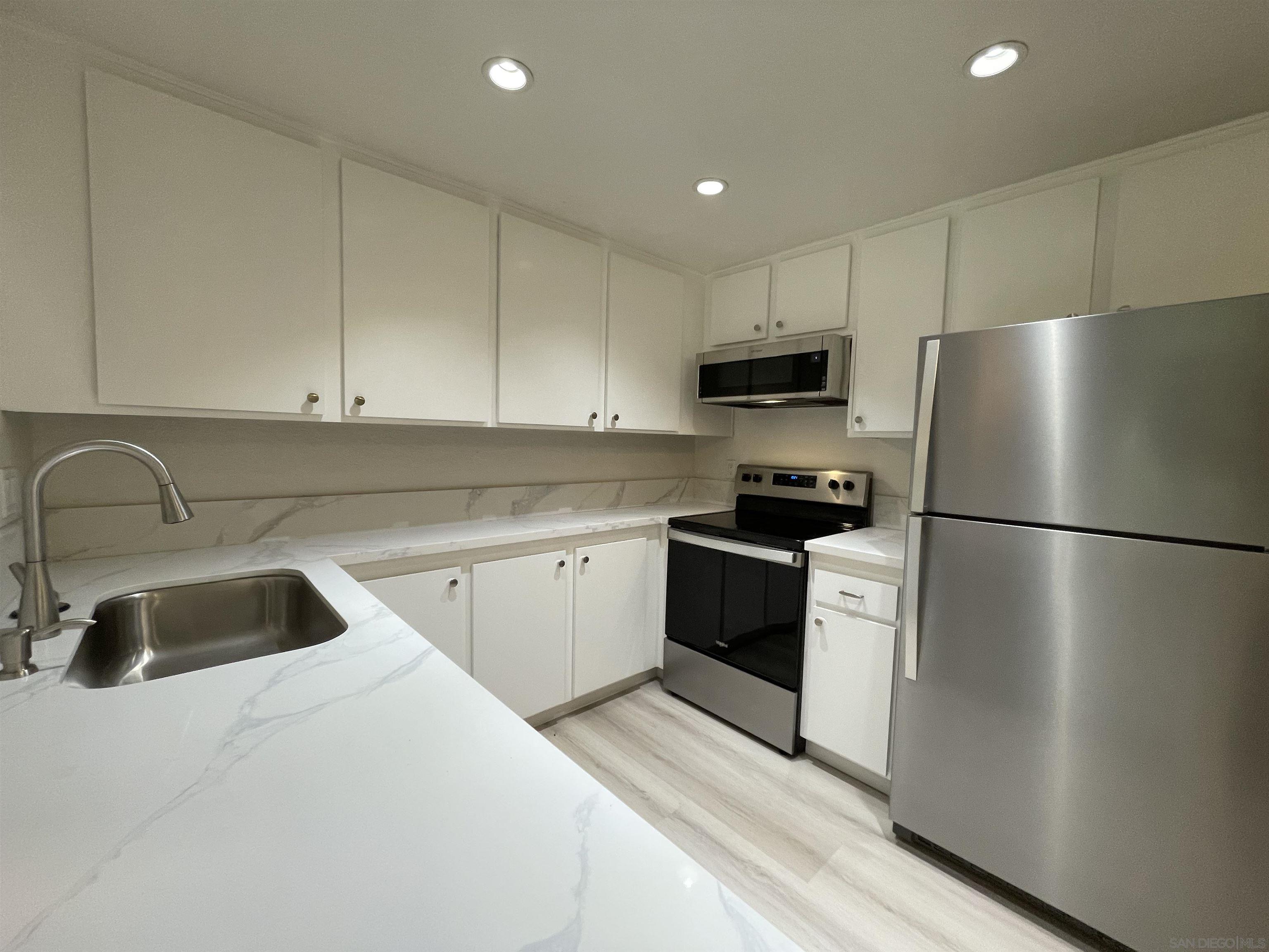 5938 Rancho Mission Road, Unit 129 San Diego, CA 92108 - Photo 29 of 29 a kitchen with refrigerator a sink and cabinets