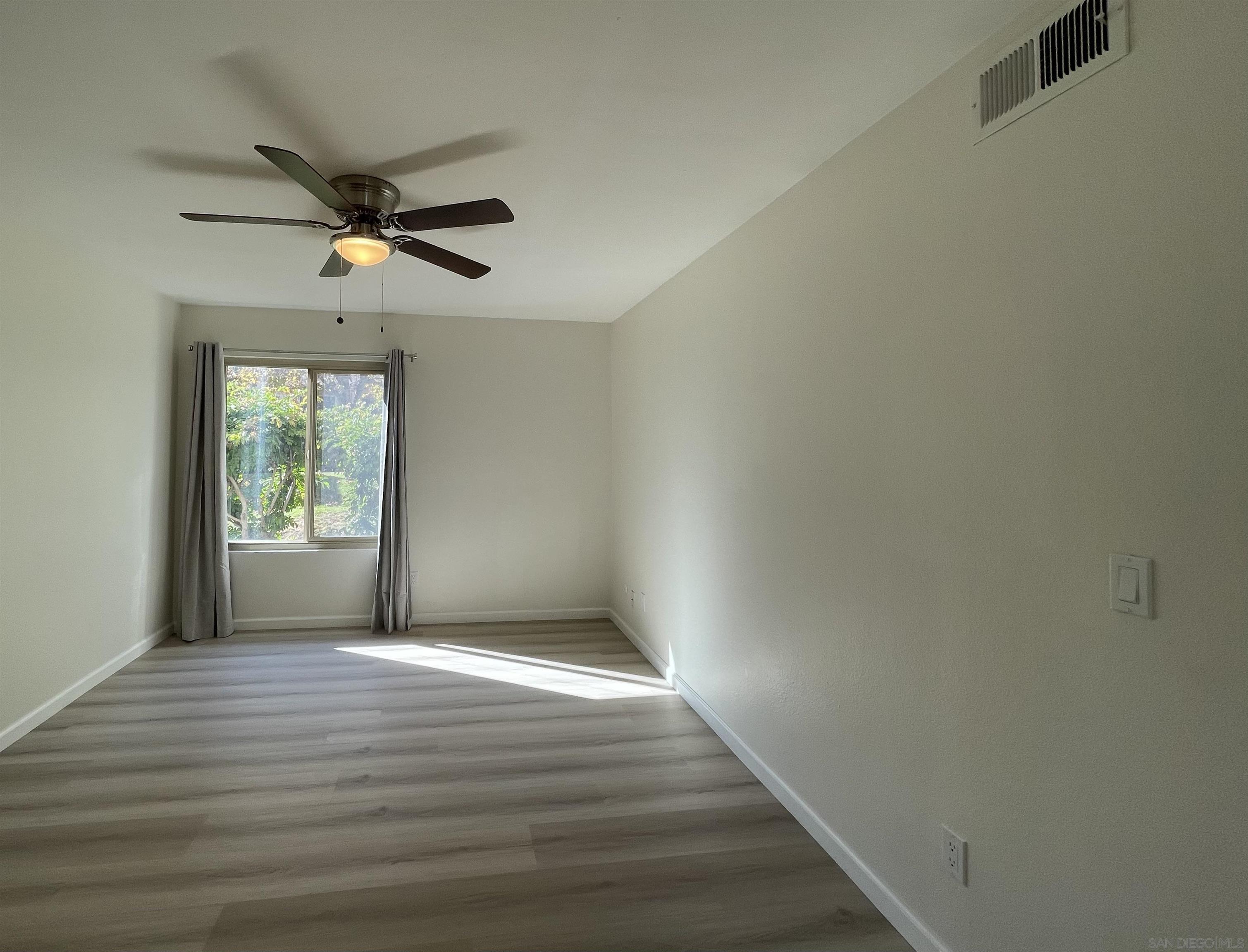 5938 Rancho Mission Road, Unit 129 San Diego, CA 92108 - Photo 9 of 29 a view of empty room with wooden floor and fan