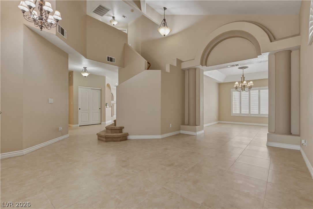 29 Olive Tree Henderson, NV 89074 - Photo 7 of 60 This grand foyer showcases soaring ceilings, an elegant staircase, and a formal dining area beyond an arched entryway.