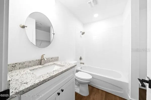 a bathroom with a granite countertop sink a toilet and a bathtub