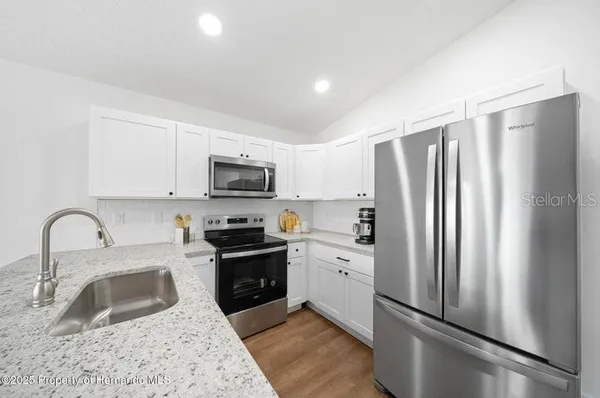 a kitchen with stainless steel appliances granite countertop a refrigerator sink and stove
