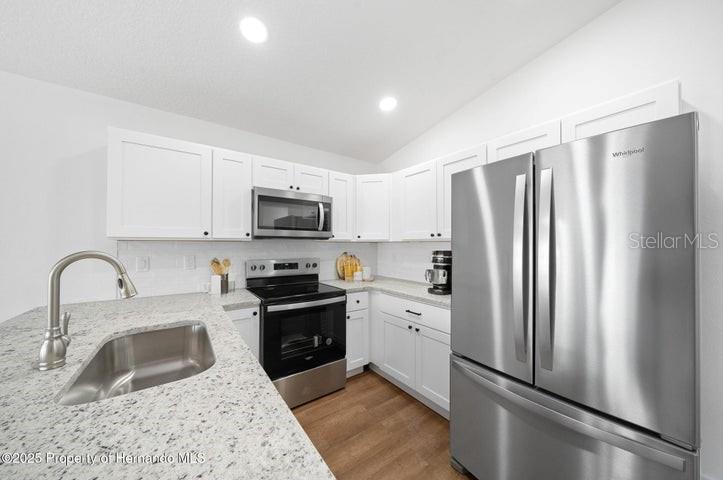 9002 Nakoma Way Weeki Wachee, FL 34613 - Photo 6 of 15 a kitchen with stainless steel appliances granite countertop a refrigerator sink and stove