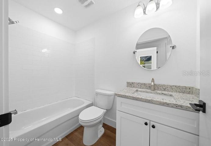 9002 Nakoma Way Weeki Wachee, FL 34613 - Photo 8 of 15 a bathroom with a granite countertop sink a toilet and a bathtub