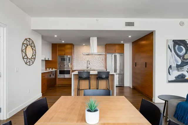 a kitchen with stainless steel appliances granite countertop a refrigerator a sink dishwasher a stove and white cabinets with wooden floor