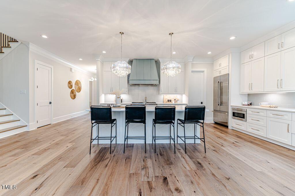2101 Gresham Lake Road Raleigh, NC 27615 - Photo 7 of 48 a open kitchen with stainless steel appliances granite countertop a stove a refrigerator a kitchen island a dining table and chairs with wooden floor