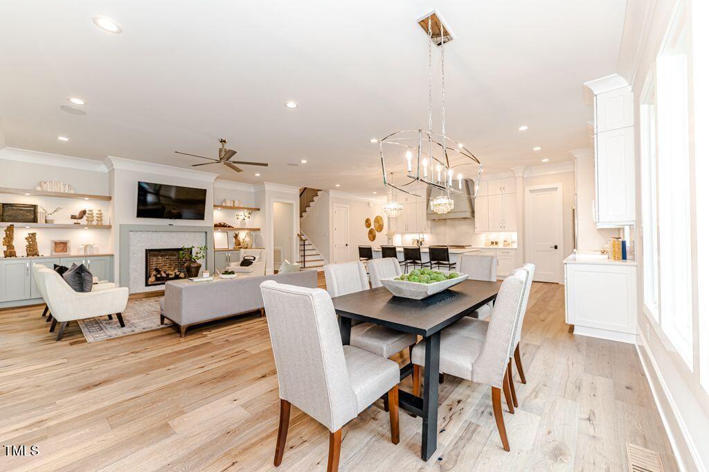 2101 Gresham Lake Road Raleigh, NC 27615 - Photo 10 of 48 a view of a dining room and livingroom with furniture wooden floor a rug a fireplace and a chandelier
