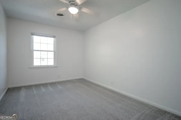an empty room with wooden floor chandelier fan and windows