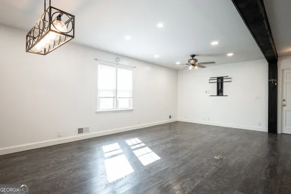 an empty room with wooden floor fan and windows
