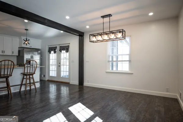 a kitchen with stainless steel appliances granite countertop a dining table chairs refrigerator and microwave