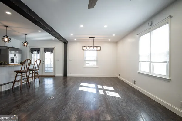 a kitchen with stainless steel appliances granite countertop a stove a refrigerator a microwave a sink a dining table and chairs with wooden floor