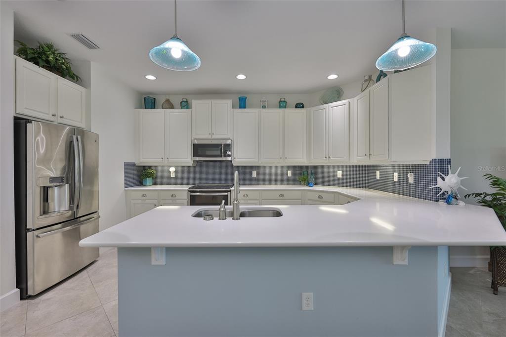 964 Pembroke Point Way Sun City Center, FL 33573 - Photo 15 of 66 a kitchen with stainless steel appliances a sink a stove a refrigerator cabinets and chairs