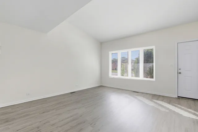 a view of an empty room with wooden floor and windows