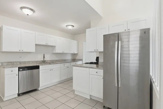 a kitchen with stainless steel appliances granite countertop a refrigerator sink and white cabinets