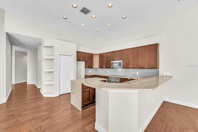 a kitchen with stainless steel appliances granite countertop a stove top oven a refrigerator a sink and dishwasher with wooden floor