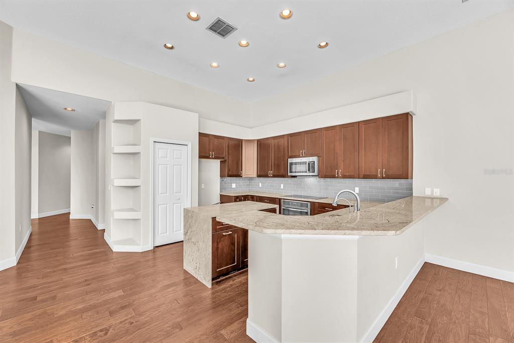 3504 Old Course Lane Valrico, FL 33596 - Photo 11 of 59 a kitchen with stainless steel appliances granite countertop a stove top oven a refrigerator a sink and dishwasher with wooden floor