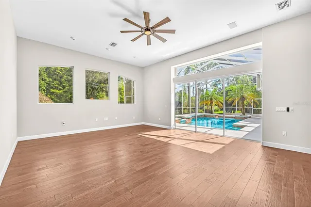 a view of an empty room with wooden floor and a kitchen