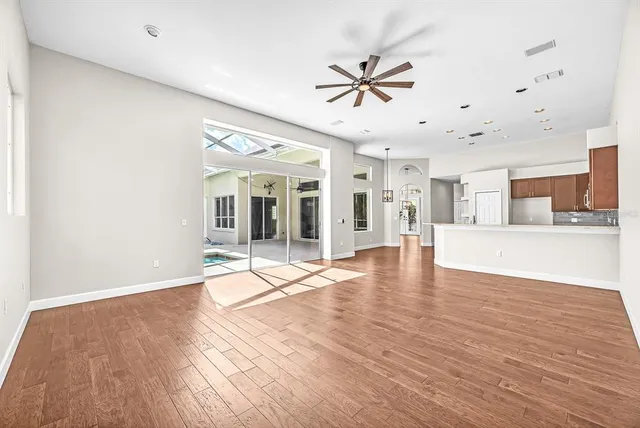 an empty room with wooden floor and windows
