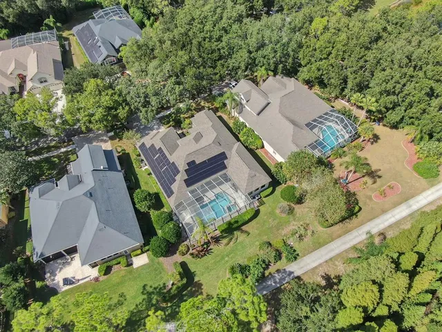a view of a house with a big yard plants and large trees