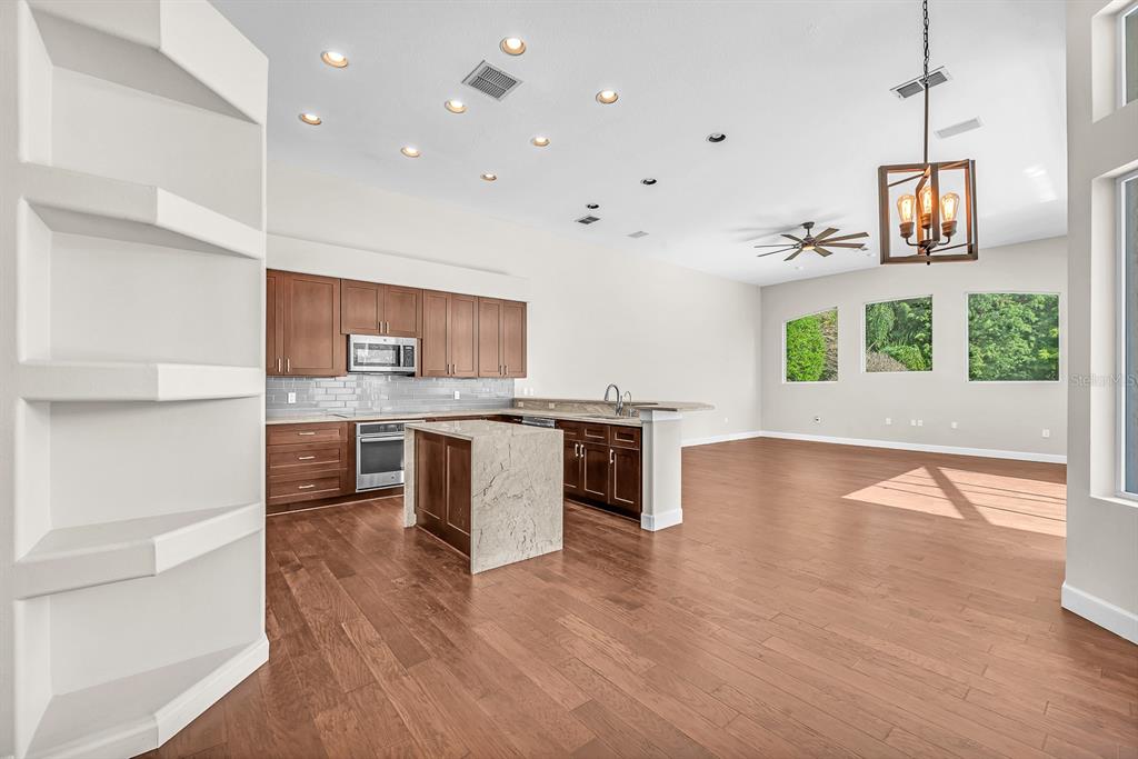 3504 Old Course Lane Valrico, FL 33596 - Photo 10 of 59 a open kitchen with stainless steel appliances granite countertop a stove top oven a sink and a wooden floors