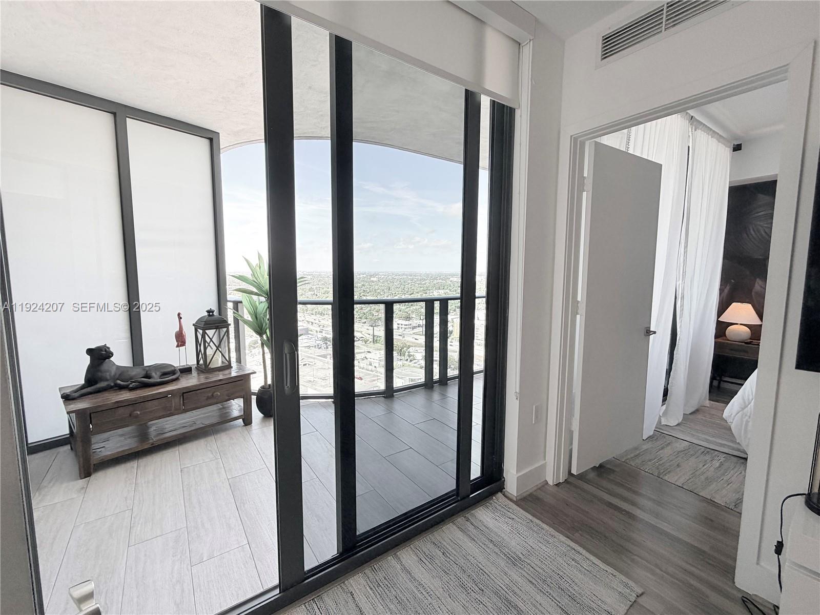 121 Northeast 34th Street, Unit 3014 Miami, FL 33137 - Photo 49 of 54 a view of a living room with a floor to ceiling window and wooden floor