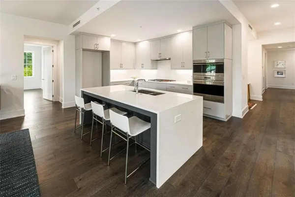 a kitchen with stainless steel appliances kitchen island granite countertop a table chairs refrigerator and a sink