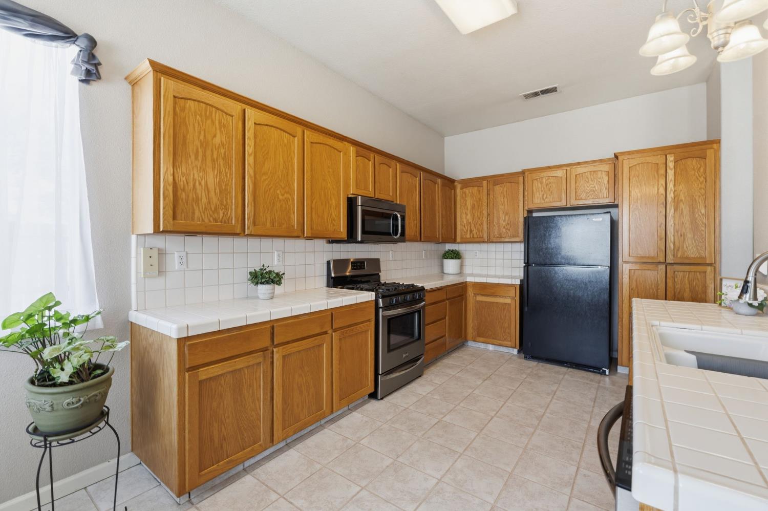 1757 Homestead Way Lemoore, CA 93245 - Photo 11 of 35 a kitchen with a refrigerator and a stove top oven