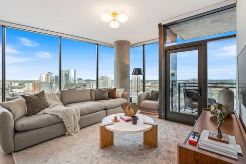 a living room with furniture large windows and wooden floor