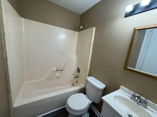 a white toilet sitting next to a bath tub