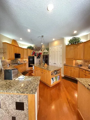 a large kitchen with stainless steel appliances kitchen island granite countertop a large counter top and stove