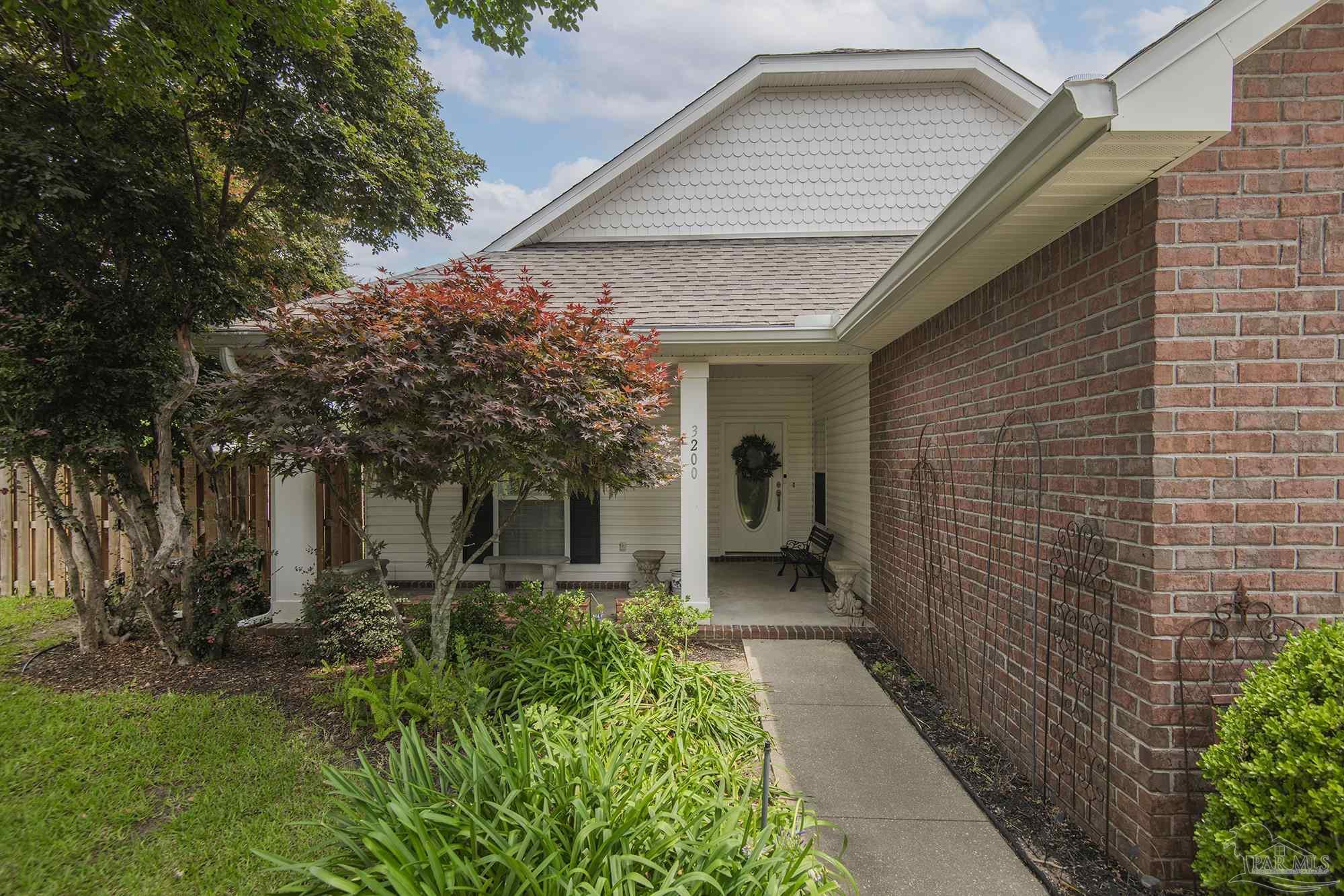 3200 Silverleaf Drive Pensacola, FL 32504 - Photo 1 of 38 a backyard of a house with plants and tree with wooden fence