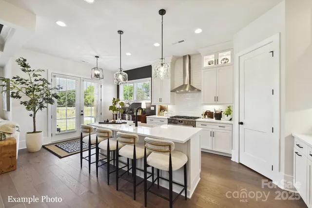 a kitchen with stainless steel appliances kitchen island a table chairs and a refrigerator