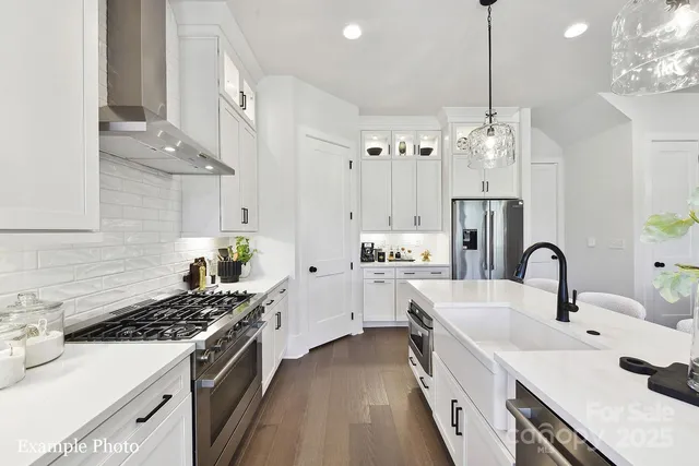 a kitchen with stainless steel appliances a sink stove and white cabinets next to a window