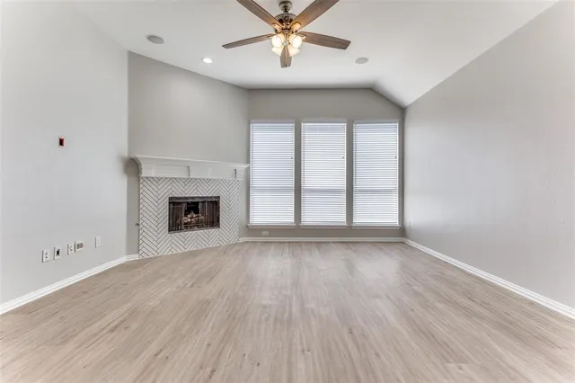 an empty room with windows and fireplace