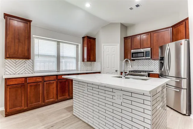 a kitchen with stainless steel appliances granite countertop a sink stove refrigerator and cabinets