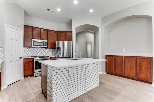 a kitchen with stainless steel appliances granite countertop wooden cabinets a stove a sink and a refrigerator