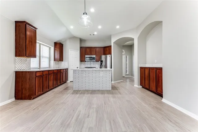 a kitchen with stainless steel appliances granite countertop a refrigerator oven a sink dishwasher and wooden cabinets with wooden floor