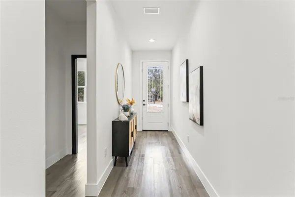 a view of a hallway with wooden floor and a living room