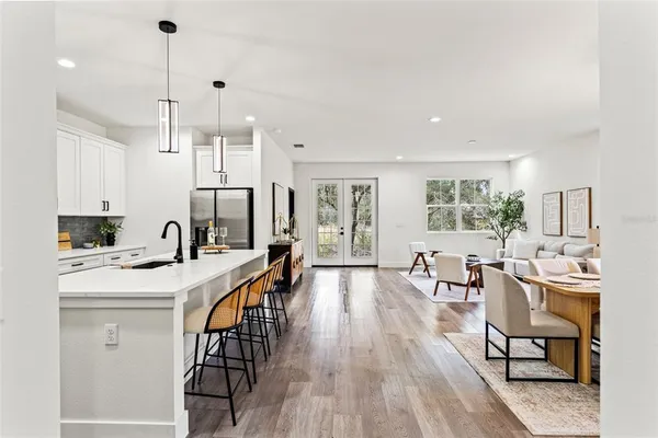 a open kitchen with stainless steel appliances granite countertop a stove a sink a dining table and chairs with wooden floor